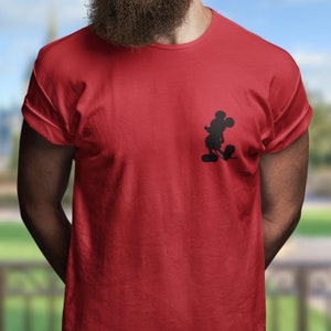 Puede incluir: Una camiseta roja con una silueta negra de Mickey Mouse en el lado izquierdo del pecho.