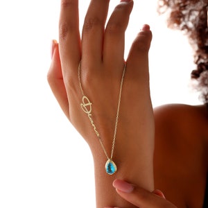 May include: A gold necklace with a teardrop-shaped blue gemstone pendant and the name "Diana" spelled out in cursive.