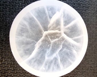 May include: A white alabaster bowl with a unique, natural, swirling pattern. The bowl is round and has a smooth, polished finish.