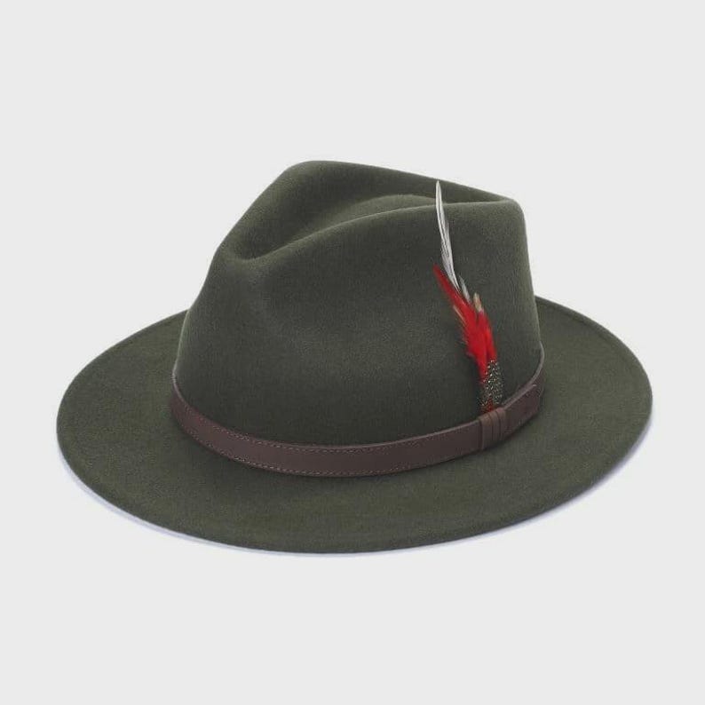 Peut inclure: Chapeau fedora vert fonc&eacute; avec un bandeau en cuir marron. Une plume rouge et blanche est attach&eacute;e sur le c&ocirc;t&eacute;. Le chapeau a un large bord et une couronne l&eacute;g&egrave;rement creus&eacute;e.
