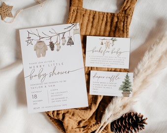 May include: A white baby shower invitation with a watercolor illustration of a baby onesie hanging on a branch with other Christmas ornaments. The invitation reads "Please join us for a Merry Little Baby Shower" and includes the names Taylor & Sam, the date and time of the shower, and the location. There are two smaller cards, one for a book request and one for a diaper raffle.