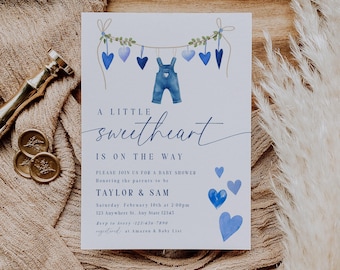 May include: A baby shower invitation with a blue and white color scheme. The invitation features a string of blue hearts with a pair of blue overalls hanging from it. The text on the invitation reads "A little sweetheart is on the way."  The invitation also includes the names "Taylor & Sam" and the date and time of the baby shower.