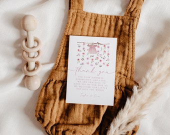 May include: A thank you card with a watercolor illustration of a pink baby dress hanging on a clothesline with pink flowers and butterflies. The text on the card reads "Thank you for your kindness, generosity and love. We are grateful to have you by our side as we welcome our little one into the world. Tayler & Son."