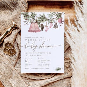 Christmas baby shower invitation with watercolor pine branches, pink baby dress, socks, ornaments, and rustic holiday décor. Text reads ‘Merry Little Baby Shower’ with event details.