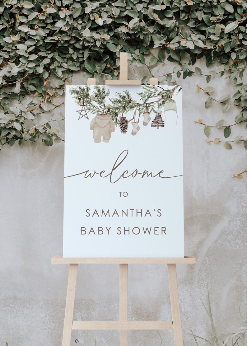May include: Welcome to Samantha's Baby Shower sign featuring a watercolour illustration of a pine branch with decorations including a baby onesie, a pine cone, a sock, a stocking, and a small Christmas tree.