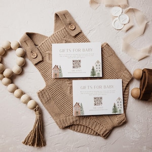 Puede incluir: Un pelele de bebé tejido de color marrón con botones de madera, junto con dos tarjetas que dicen "REGALOS PARA BEBÉ". Las tarjetas presentan ilustraciones de casas y árboles. También hay una guirnalda de cuentas de madera y un coche de juguete.