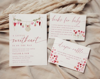 May include: A baby shower invitation with a pink and white color scheme. The invitation features a watercolor illustration of a baby onesie hanging from a string of hearts. The text reads "A little sweetheart is on the way".
