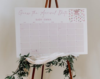 May include: A pink and white calendar with the text "Guess the Arrival Date of Baby Emma" at the top. The calendar is on a wooden easel with greenery and a white fabric draped over it.