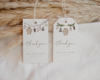 Könnte beinhalten: Zwei weiße Dankeschön-Etiketten mit einem Winter-Babyparty-Thema. Die Etiketten zeigen eine Aquarell-Illustration eines Baby-Bodys, der an einem Zweig mit anderen winterlichen Dekorationen hängt. Der Text auf den Etiketten lautet "Danke" und "Sams Babyparty, 18. Dezember 20XX".