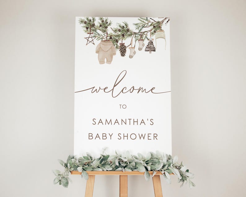 May include: Welcome to Samantha's Baby Shower sign featuring a watercolour illustration of a pine branch with decorations, including a baby onesie, a stocking, a pine cone, and a star.