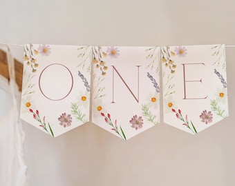May include: A white banner with a floral design and the word "ONE" in pink lettering. The banner is perfect for a first birthday party.