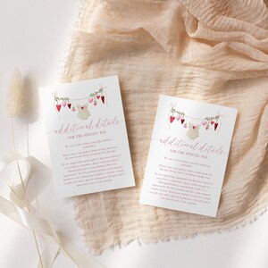 May include: Two white cards with the text "additional details for the special day" are displayed on a beige fabric. The cards feature a garland of hearts and a baby onesie illustration. Decorative dried flowers and ribbon are also present.