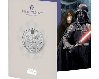 Può includere: Una moneta d'argento con Darth Vader e un personaggio di Star Wars. La moneta è in una teca con un'immagine di sfondo di Darth Vader e un altro personaggio di Star Wars. Il testo "THE ROYAL MINT" e "STAR WARS" è sulla teca.