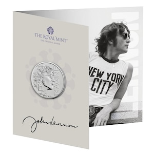 Könnte beinhalten: Eine Gedenkmünze mit dem Profil von John Lennon, den Worten "JOHN LENNON IMAGINE" und einer Unterschrift. Die Münze wird in einer Karte mit dem Logo "THE ROYAL MINT" und einem Schwarz-Weiß-Bild von John Lennon mit einem "NEW YORK CITY"-Shirt präsentiert.