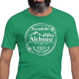 May include: A green t-shirt with a white graphic of a mountain range, a barrel, and snowflakes. The text on the graphic reads "Arendelle Alehouse, Where the cold never bothers you."