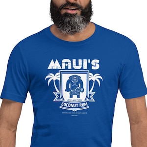 May include: A royal blue t-shirt with a white graphic of a cartoon character with a shield and palm trees. The text "Maui's Coconut Rum" is printed on the shirt.
