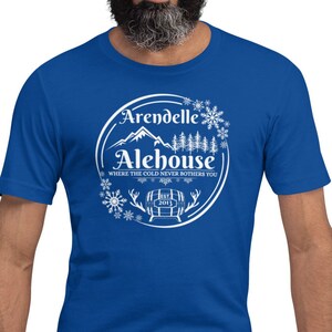 May include: A royal blue t-shirt with a white graphic of a mountain scene and the text "Arendelle Alehouse, Where the cold never bothers you".