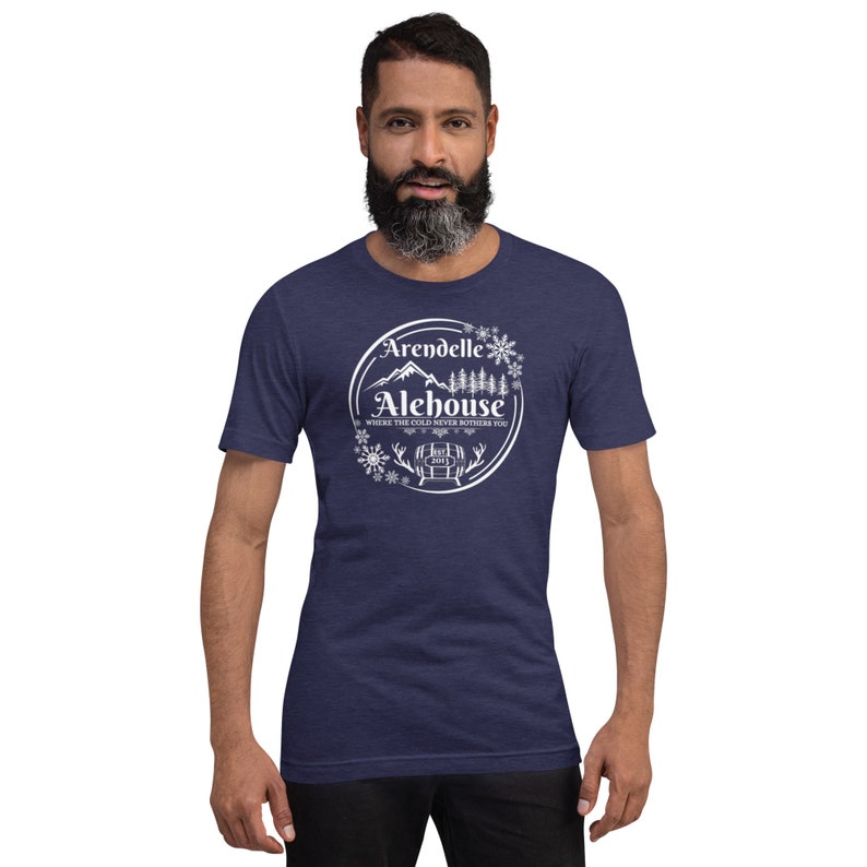 May include: A navy blue t-shirt with a white graphic of a mountain scene and the text "Arendelle Alehouse, Where the cold never bothers you".