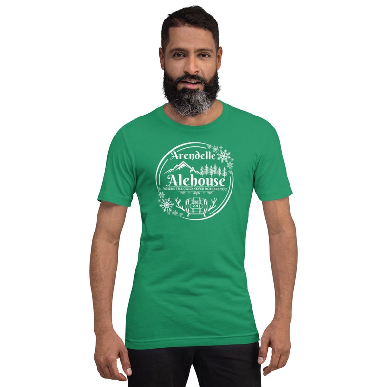 May include: A green t-shirt with a white graphic of a mountain range, a barrel, and snowflakes. The text on the graphic reads "Arendelle Alehouse, Where the cold never bothers you."