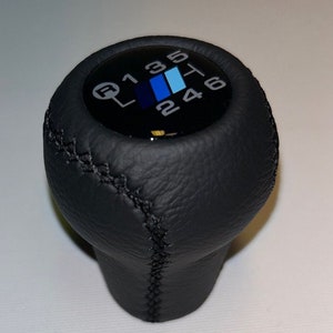 May include: Black leather gear shift knob with a black and white gear pattern and the numbers 1, 2, 3, 4, 5, and 6.