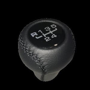 Op de afbeelding: Zwarte lederen versnellingspookknop met witte versnellingspatroonmarkeringen. Het versnellingspatroon omvat achteruit, eerste, tweede, derde, vierde en vijfde versnelling. De knop heeft een gestikte naad.