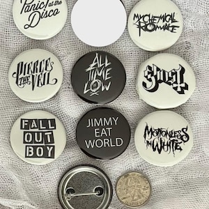 May include: A collection of 10 round black and white buttons with band names and logos. The buttons feature bands such as Panic! At The Disco, My Chemical Romance, Pierce The Veil, All Time Low, Ghost, Fall Out Boy, Jimmy Eat World, and Motionless In White.
