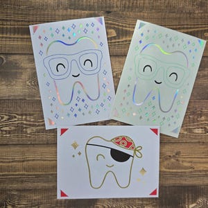 May include: Three holographic cards with a tooth design. The tooth on the left card is wearing glasses, the tooth on the right card is wearing glasses, and the tooth on the bottom card is wearing an eye patch and a red bandana.