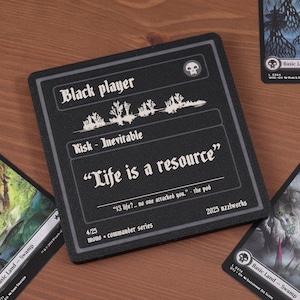 May include: A black player card with the text "Life is a resource" in white, surrounded by other Magic: The Gathering cards. The card has a skull icon and the text "Risk - Inevitable".