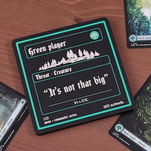 May include: Black card with green trim and text that reads "Green player" and "It's not that big." Forest cards are scattered around the main card. The main card has a forest graphic.