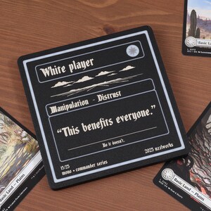 May include: A black and white card with the text "White player" and "Manipulation - Distrust". The quote "This benefits everyone" is featured. The card is surrounded by other cards with landscape art.