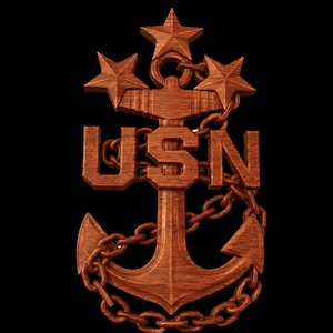 May include: A carved wooden emblem featuring a central anchor wrapped in a chain, topped with three five-pointed stars, and displaying the letters USN in a bold, block font across the centre of the anchor shank against a black background.