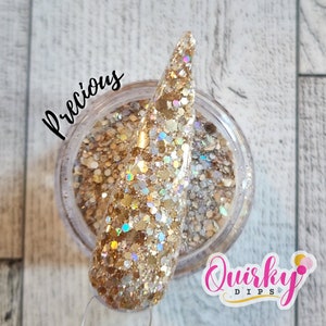 Könnte beinhalten: Ein Glas goldfarbenes Glitzer-Nagelpulver mit dem Wort "Precious" in Schreibschrift. Ein Nagelmuster ist in den Glitzer getaucht. Das Logo "Quirky Dips" befindet sich in der unteren rechten Ecke.
