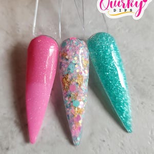 May include: Three nail dip powder colours: a light pink with a gradient, a light blue with glitter, and a teal with glitter. The colours are displayed on clear plastic sticks. The text "Quirky Dips" is visible in the top right corner of the image.