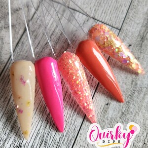 May include: Five different colors of nail dip powder displayed on clear plastic sticks. The colors are beige with gold glitter, hot pink, coral with gold glitter, orange, and a clear glitter with gold and iridescent glitter. The colors are arranged in a fan shape. The text "Quirky Dips" is visible in the lower right corner of the image.