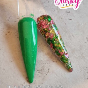 May include: Two nail dip colors, one green and one with red, green, and gold glitter. The text "Taurus Duo" is below the colors. The text "Quirky Dips" is in the upper right corner of the image.