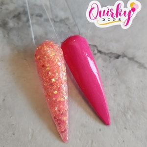 May include: Two nail dip samples, one is a pink glitter and the other is a solid hot pink. The samples are on a white surface with the text "Quirky Dips" in a white circle with a pink outline.