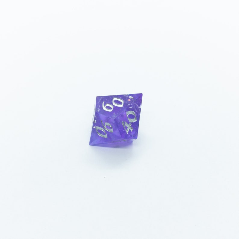 May include: A purple, iridescent, six-sided die with white numbers. The die is showing the number 40.