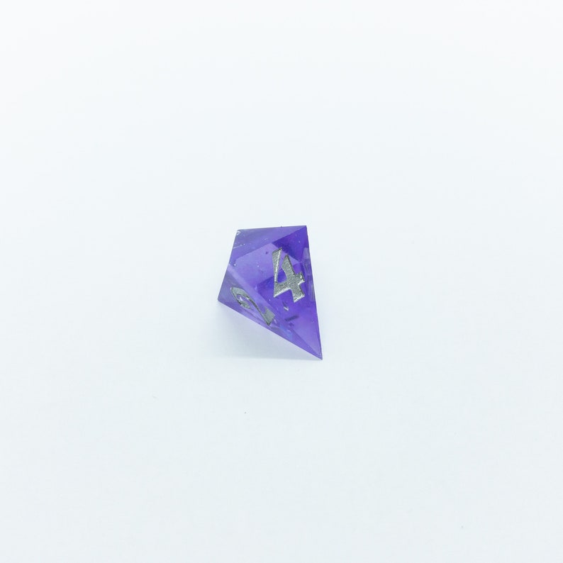 May include: A purple four-sided dice with silver numbers.