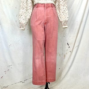 May include: High-waisted, wide-leg pants in a light pink color. The pants have a relaxed fit and a straight leg.