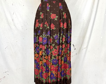 May include: A long, brown skirt with a floral design. The skirt has a repeating pattern of red, blue, and orange flowers on a dark brown backdrop. The skirt is pleated and seems to be made of a lightweight material.