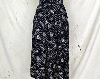 Könnte beinhalten: Ein marineblauer Midirock mit floralem Muster. Der Rock hat eine hohe Taille und eine volle, fließende Silhouette. Das florale Design umfasst kleine weiße und rosa Blüten, die über den Stoff verstreut sind.