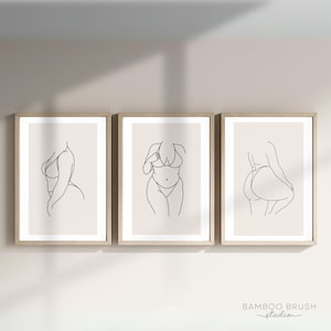 May include: Three framed line drawings of a person in a swimsuit. Each drawing shows a different pose of the person. The drawings are on a light beige background and are framed in a light wood frame.