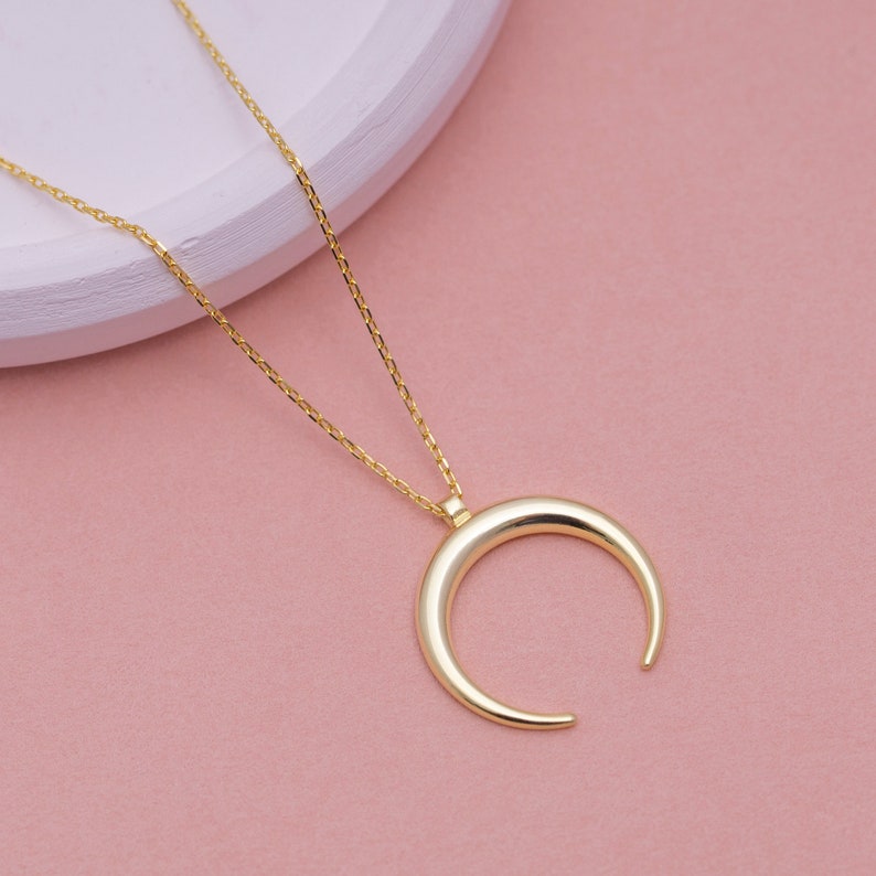 May include: A gold crescent moon pendant necklace with a delicate chain.