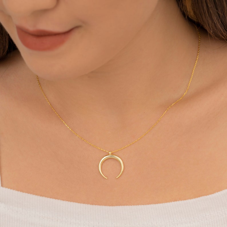 May include: A gold chain necklace with a crescent moon pendant.