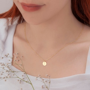 May include: A gold chain necklace with a small round pendant featuring the letter "J" engraved on it.
