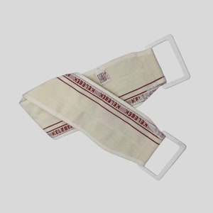 May include: White bath scrub with red trim and the word "Kelebek" repeated along the trim. The scrub has two white plastic loops for hanging.