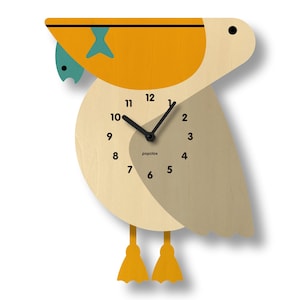 May include: A wooden wall clock shaped like a puffin with a yellow beak and a blue fish in its beak. The clock face is white with black numbers and hands. The clock says "popclix" on the face.