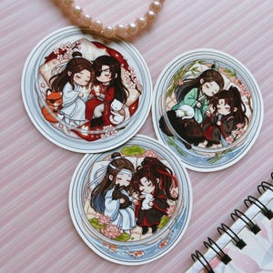 May include: Three circular stickers featuring chibi-style anime characters in pairs. Each sticker depicts two figures in traditional robes resting with small animals, surrounded by floral elements like cherry blossoms, bamboo, and lotus flowers.