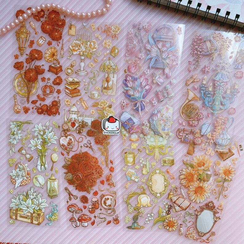 May include: A sheet of clear, transparent stickers with a variety of floral and vintage-inspired designs. The stickers feature images of roses, lilies, sunflowers, birds, cages, books, and other decorative elements. The stickers are perfect for adding a touch of whimsy and charm to journals, planners, and other craft projects.