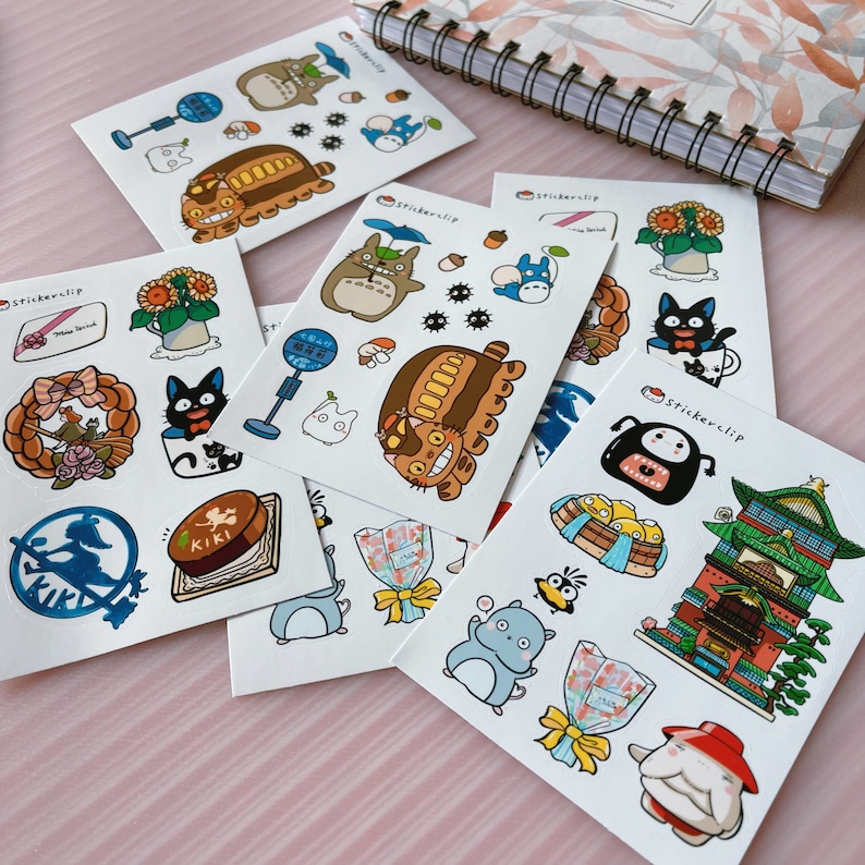 May include: A set of 10 sticker sheets featuring characters from the Studio Ghibli films, including Totoro, Kiki's Delivery Service, and Spirited Away. The stickers are printed on white paper and have a glossy finish. The sticker sheets are packaged in clear plastic sleeves.
